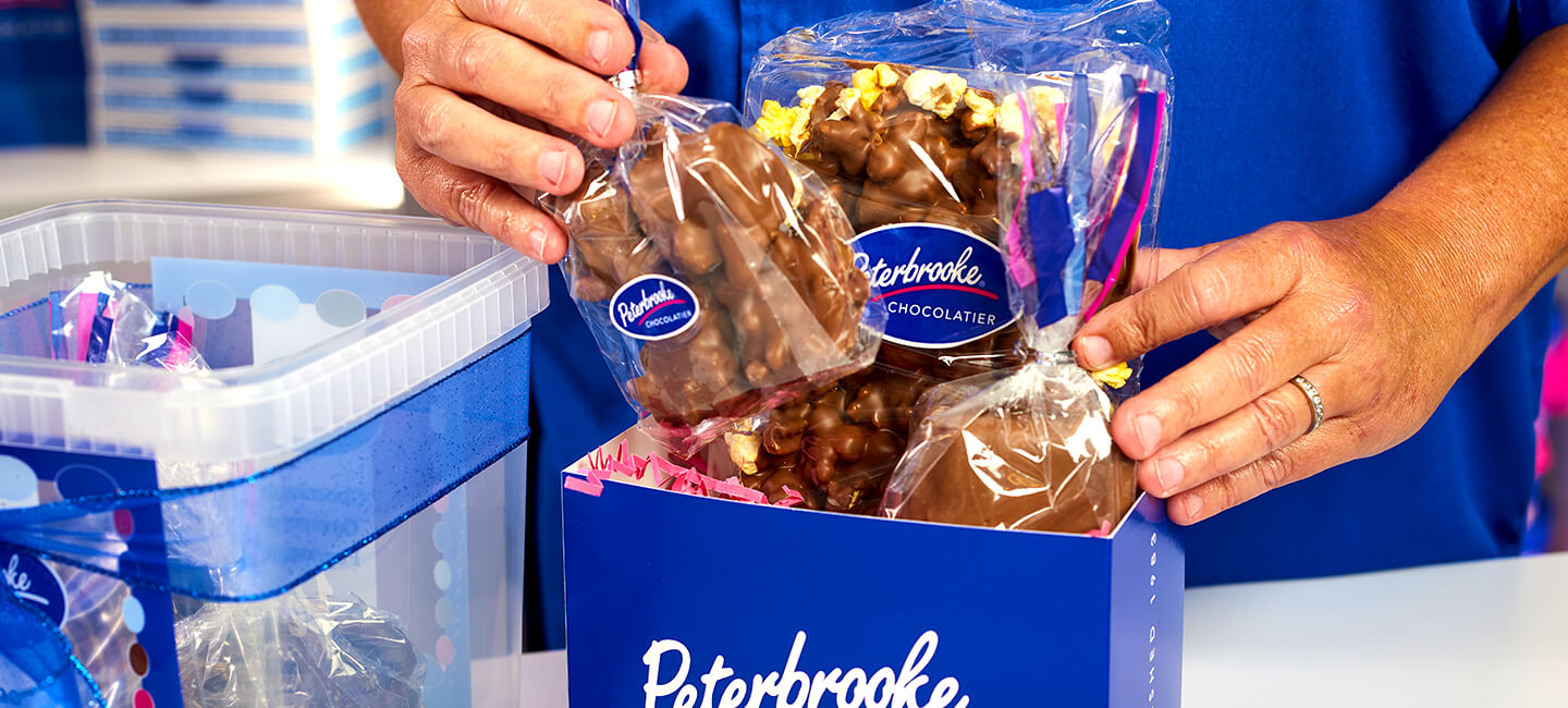 Handcrafted chocolate being added to a gift box.